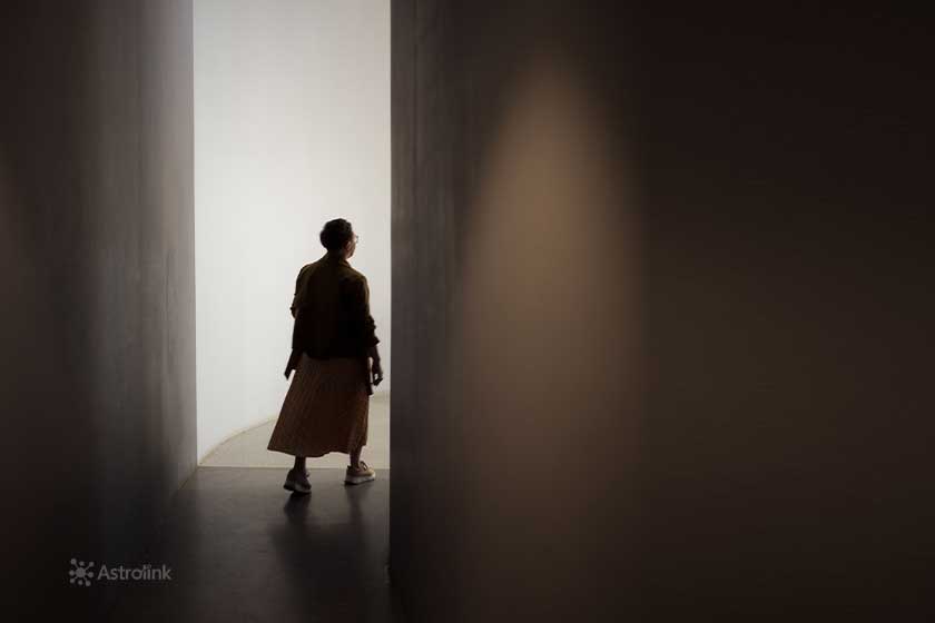 woman walking out a door into the light, representing leaving the comfort zone